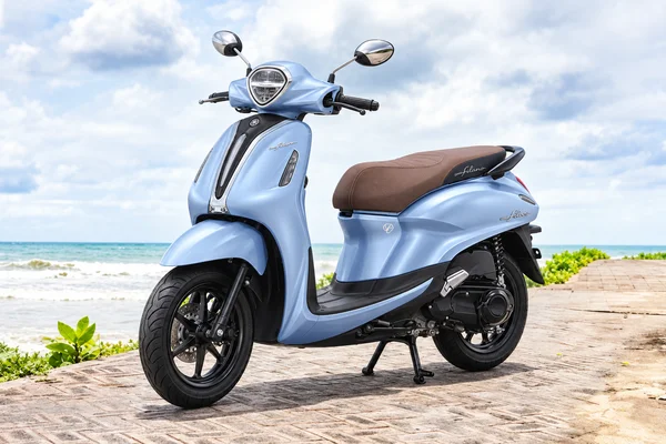 Blue Yamaha Grand Filano125 with brown seat, front-left view, beside the ocean