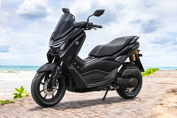 Black Yamaha NMAX155 Neo, front-left view, beside the ocean