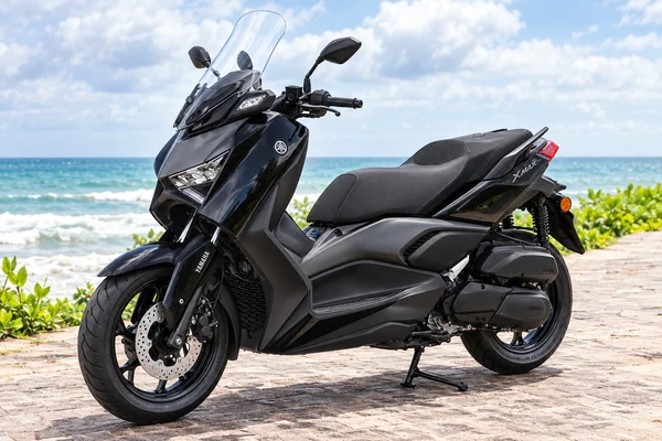 Black Yamaha XMAX 250 Connected, front-left view, beside the ocean